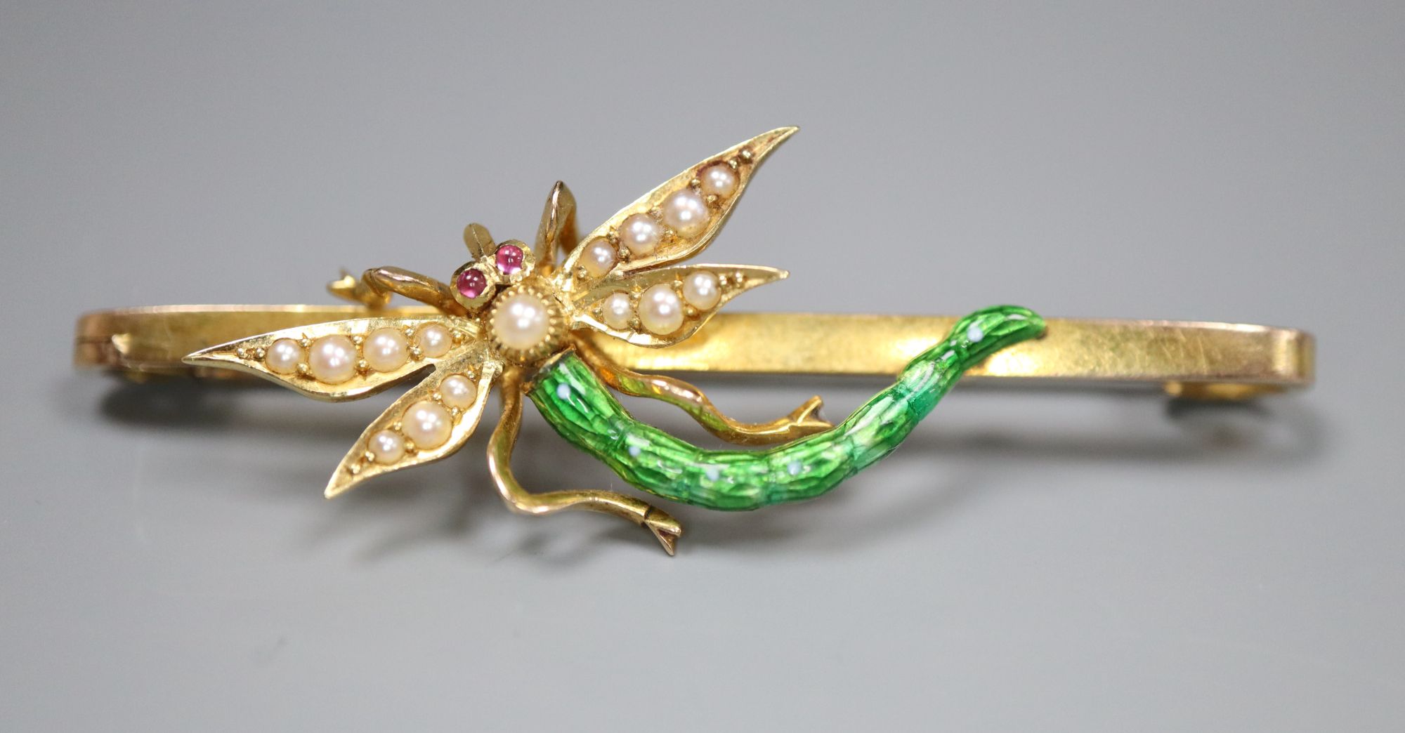 An Edwardian yellow metal, garnet?, seed pearl and green enamel set dragonfly bar brooch, 51mm, gross 6.7 grams.